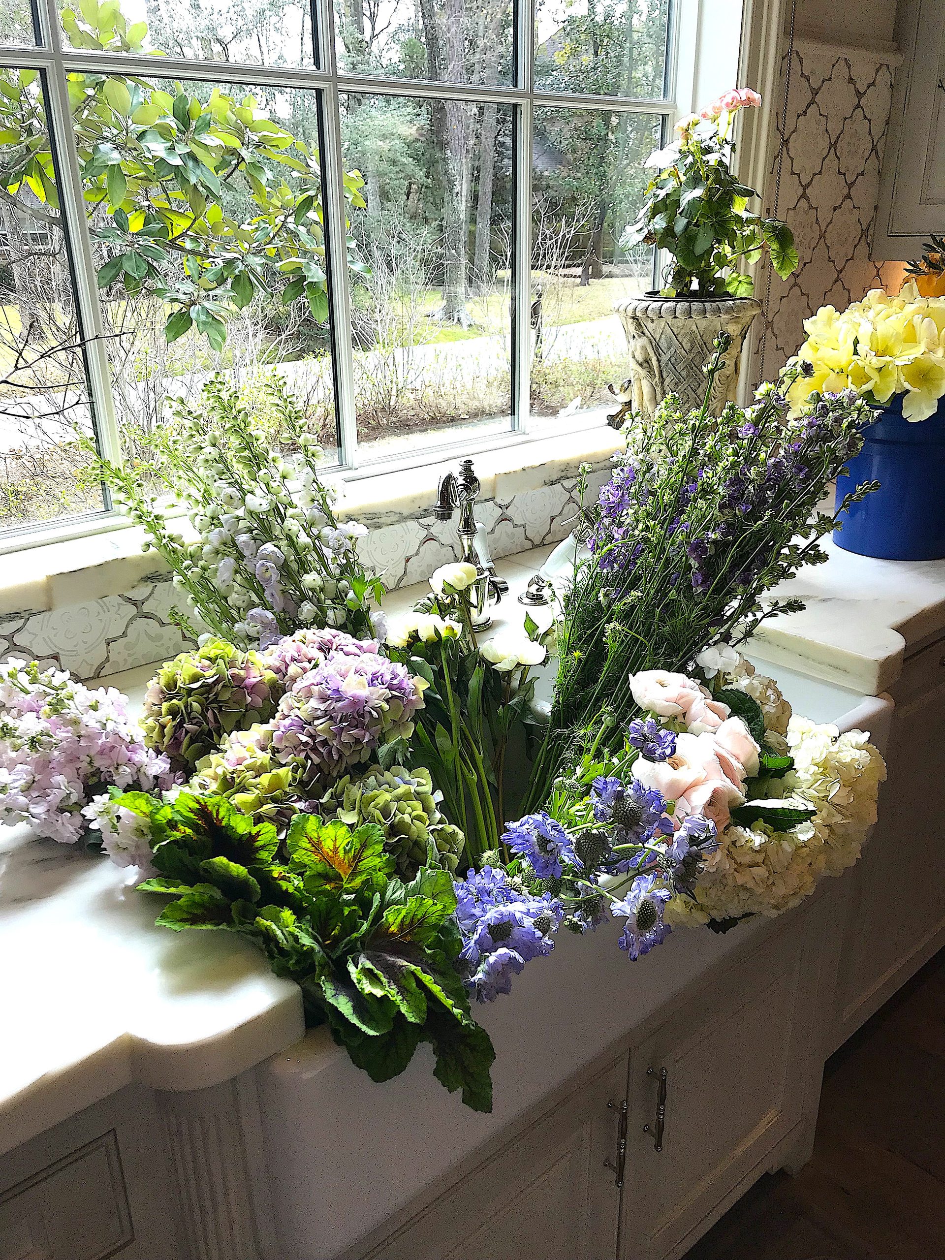 Fresh photo shoot flowers and floral stems are soaking in a sink while being prepped for magazine location styling.